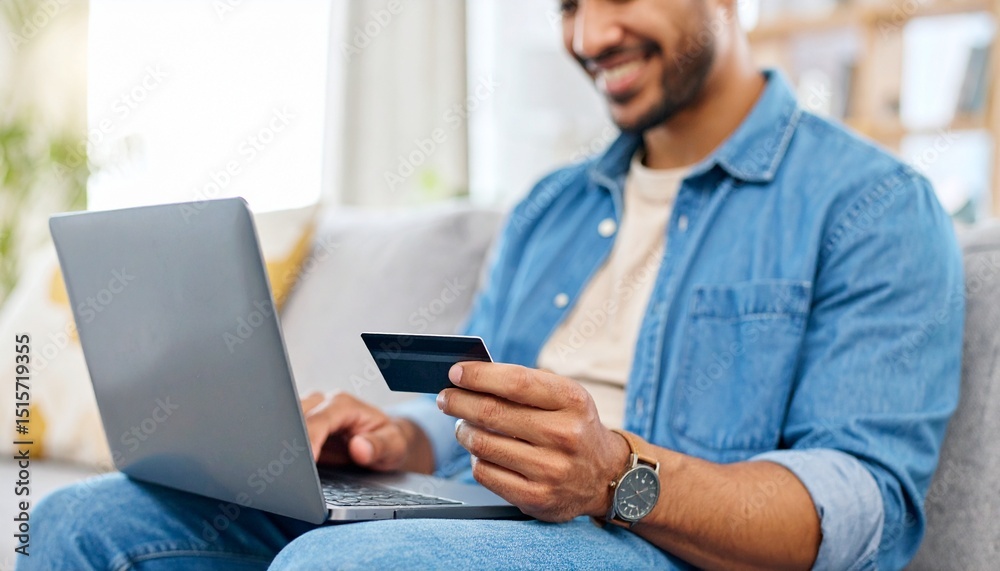 Smiling man using a laptop to do online shopping and holding a credit card Smiling man using a laptop to do online shopping and holding a credit card