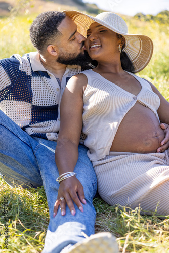 On a joyful summer day, a couple enjoys natures beauty, cherishing their love and the exciting journey ahead as they prepare for their baby, savoring this remarkable moment under the blue sky