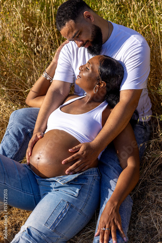 A pregnant couple enjoys a beautiful summer day outdoors, radiating joy and celebrating their love, while nurturing excitement for their childs imminent arrival in a lovely natural setting