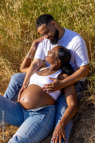 An African American couple joyfully celebrates their pregnancy outdoors, embracing, laughing, and cherishing moments as they embark on a journey of love, anticipation, and a future family