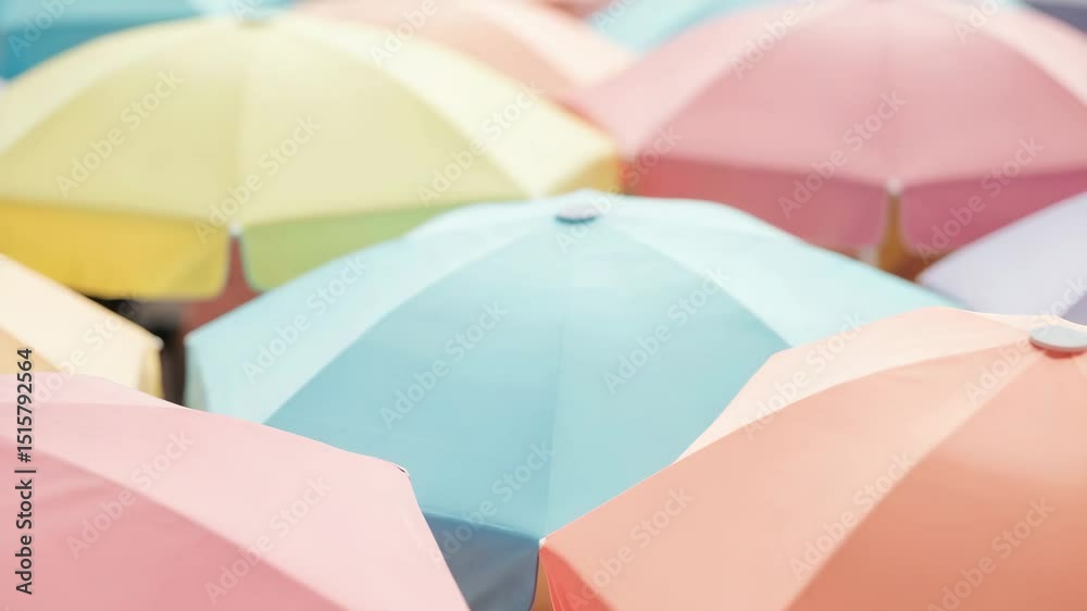 Pastel beach umbrellas crowd together, creating a colorful pattern perfect for sunny summer day