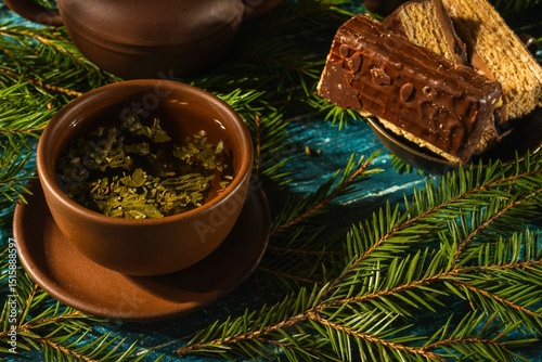 Christmas- still life with a piece of cake and morning tea. Fir tree branches- breakfast on a dark background