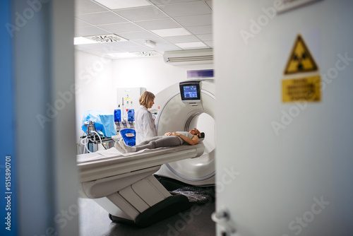 Doctor operating CT machine and preparing patient for scan photo