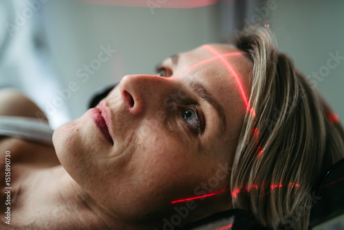 Patient positioned for head scan with laser alignment in CT scanner photo