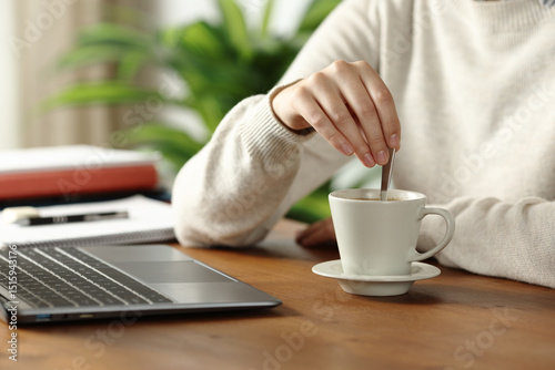 Student hand stirring coffee at home