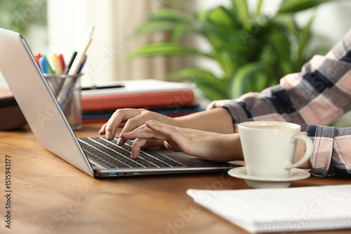 Student hands writing on laptop at home