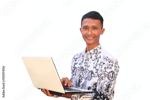 An Indonesian teacher in a PGRI uniform holding a laptop shows a happy expression