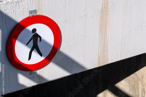 Pedestrian traffic sign on concrete wall, urban scene with shadow patterns, graphic shapes and street elements, modern minimalist design. photo
