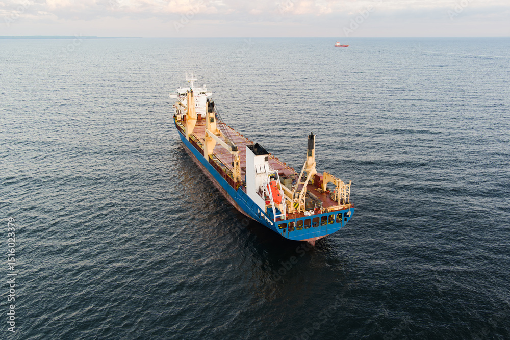 Obraz premium Aerial view of a large blue and red general cargo ship sailing on the calm waters of the Baltic Sea near the coast of Estonia.