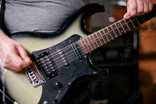 Close up of musician hands playing an electric bass guitar, focusing on precise finger placement and frets during practice session performance