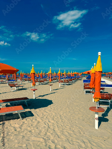 Fototapeta Naklejka Na Ścianę i Meble -  Beginning of the beach season. Empty sun loungers under umbrellas on a sandy beach.