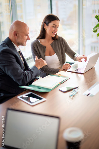 Business people sitting at office desk and using laptops and discussing