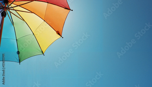 Vibrant Rainbow Umbrella in Bright Colors Against Clear Blue Sky