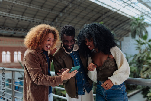 Fotografija Excited young friends looking at surprising news on smart phone screen