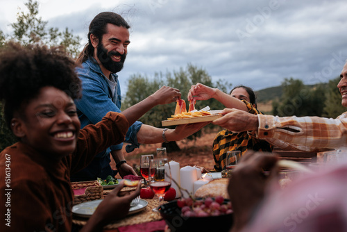 Friends sharing food, laughing and having fun at outdoor dinner party