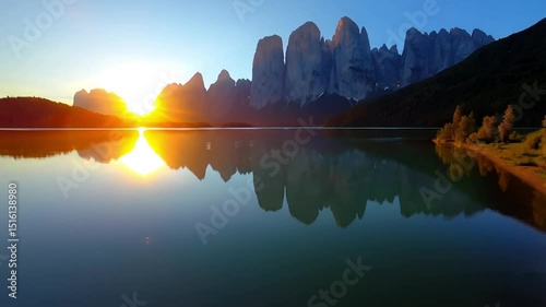 Scenic view of a lake reflecting mountains and a bright sunrise creating a serene atmosphere