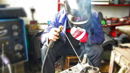 Technician worker working wearing industrial uniforms and Welded Iron Mask at Steel welding plants with sparks flying, industrial safety first concept.