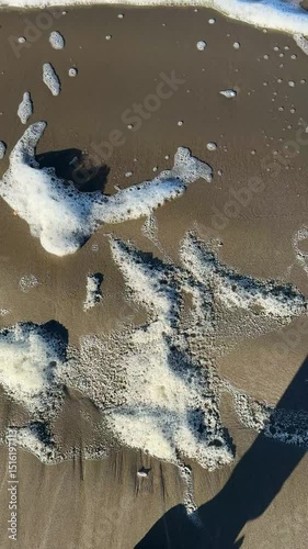 foam on the beach sand, vertical video, summer sunny day
