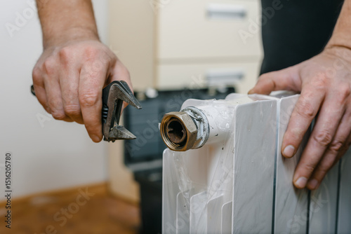 Closeup photo of man installing new heating radiator at home. Technician installing new heating radiator, unpacking and preparing for home heating setup