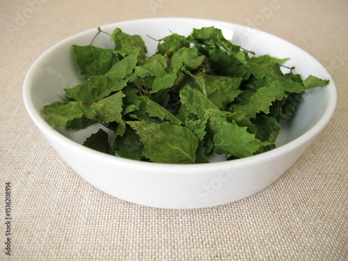 Dried birch leaves for herbal tea in a porcelain bowl