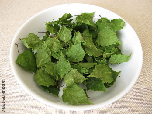Dried birch leaves for herbal tea in a porcelain bowl