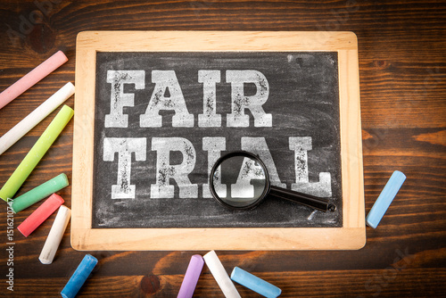 Fair Trial Concept on Blackboard with Magnifying Glass and Colored Chalk on Wooden Table photo