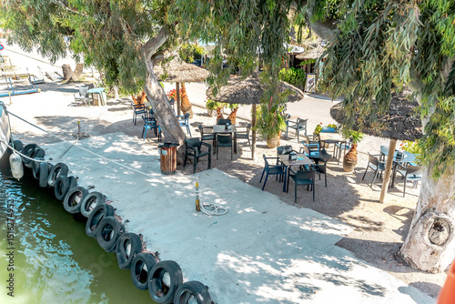 Tropical restaurant with plastic chairs and straw umbrellas on a shaded terrace