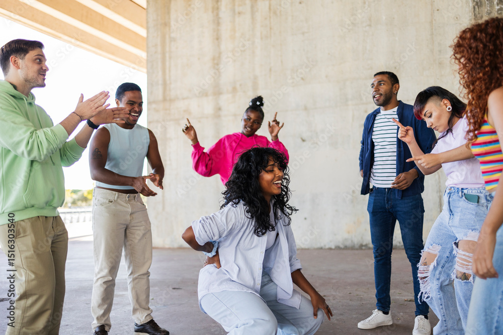 Naklejka premium Group of young people dancing and having fun under a bridge