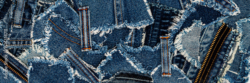 Various denim fabric pieces with frayed edges and contrasting stitching lying flat on a surface