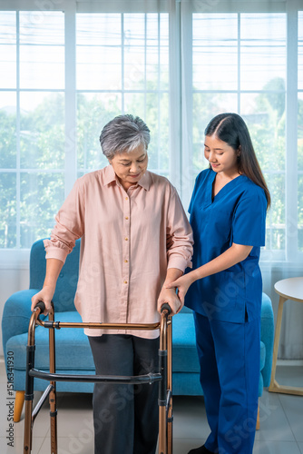 Senior elderly woman receiving walker assistance from female caregiver nurse at home