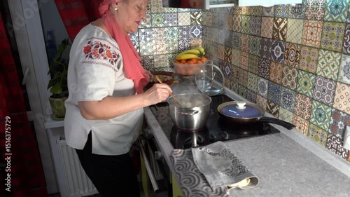Elderly woman is cooking. Grandma cooks dumplings in a saucepan. Stir with a wooden spatula on the stove. Cooking at home.
