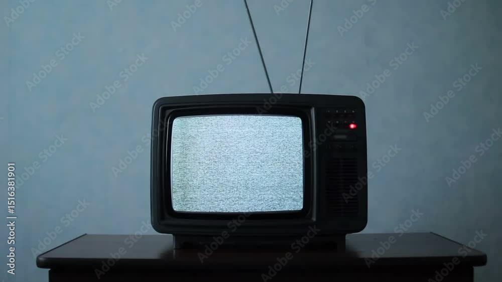 Old television with an antenna shows a screen of static snow. No signal creates white noise and flicker. A nostalgic shot for retro themes, lost communication, or suspenseful horror intros.
