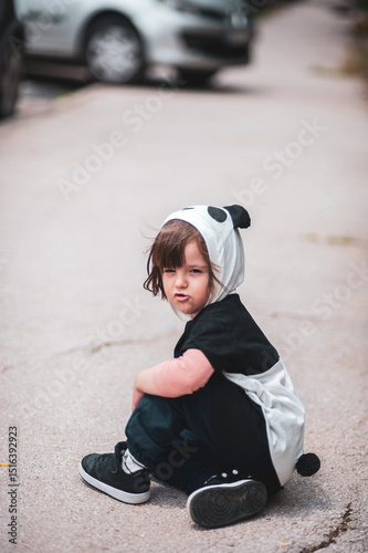 A mischievous little kid sitting on the pavement