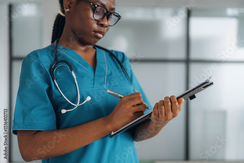 Writing information into documents. Female doctor is indoors in modern room