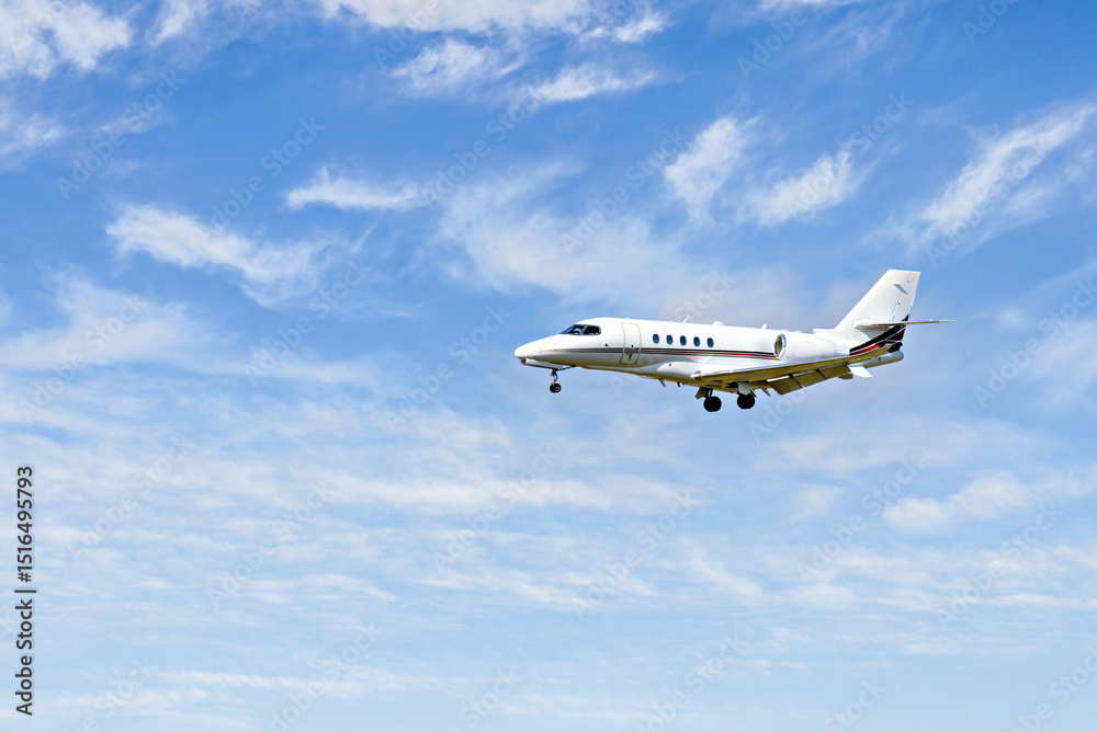 Fototapeta premium Private business plane flying under a blue sky with white clouds 