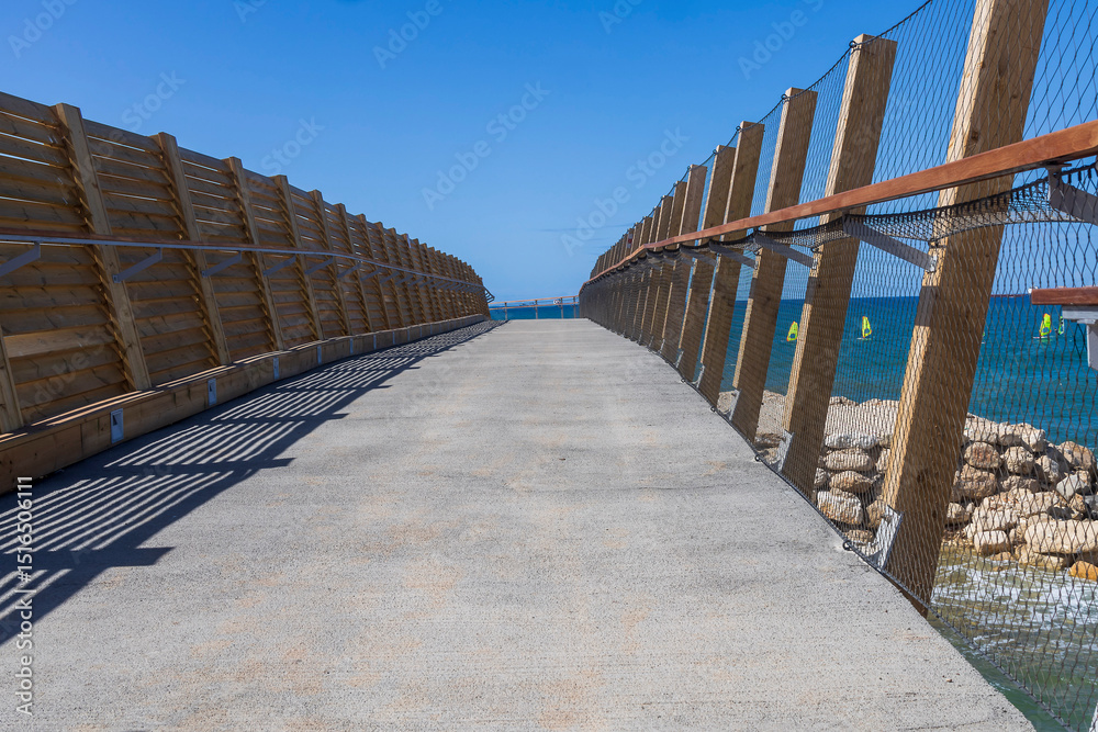 Obraz premium Pedestrian walkway along the Mediterranean Sea with wooden fencing in Haifa.