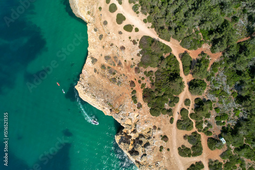 Power boat and kayaks explore the sparkling waters of the Algarve coast in Portugal