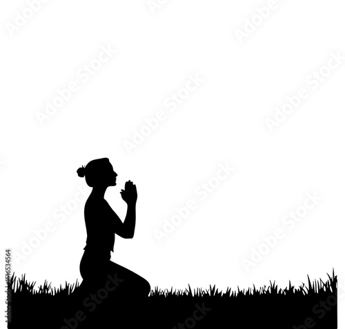 Silhouette of woman kneeling in grass with hands clasped in prayer against white