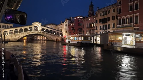 Venise, Italy: Time lapse point of view of a  vaporetto waterbus that sails along the famous Grand Canal and under the Rialto bridge at night in Venice old town in Italy.