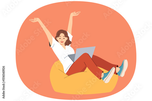 Woman freelancer joyfully raises hands after completing work on project, sitting in soft ottoman with laptop on lap. Positive girl freelancer doing distance job or receiving online education