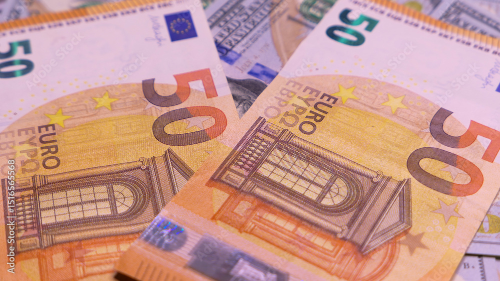 Two brightly colored 50 euro banknotes on a pile of various currency bills, emphasizing wealth and economic exchange. Text includes Two brightly colored 50 euro banknotes on a pile of various currency bills, emphasizing wealth and economic exchange. Text includes