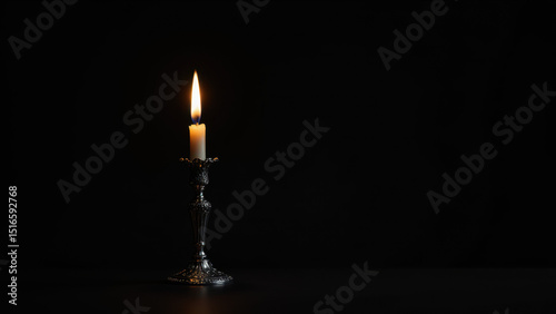A lit white candle with a black holder.