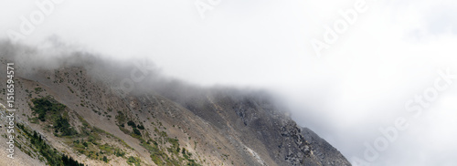 Foto Panorama of mountain scene with scree and mist on top and partly transparent sky