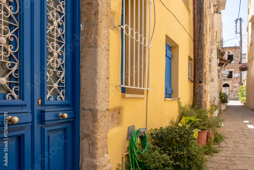 Fototapeta Naklejka Na Ścianę i Meble -  Chania old town architecture. Crete island, Greece. Blue wooden door on yellow wall, narrow cobblestone alley
