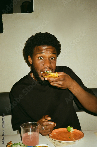 Portrait of young man eating tacos while sitting at restaurant