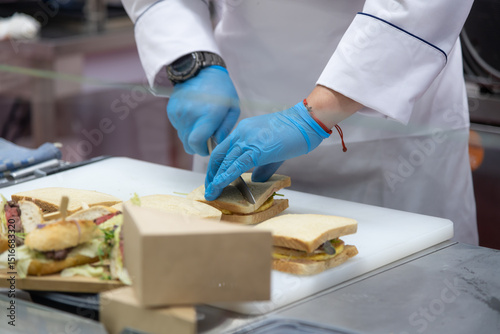 Chef prepares sandwiches in a commercial kitchen during busy lunch hour