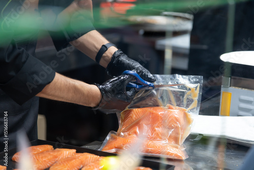 Chef preparing fresh salmon fillets in a commercial kitchen at lunchtime