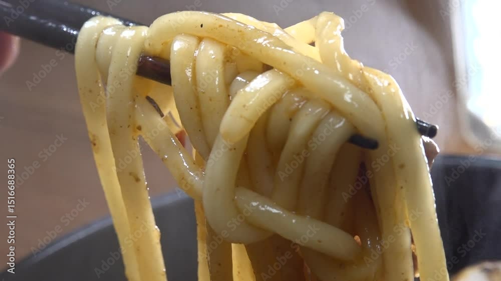 Steaming udon noodles being lifted with chopsticks