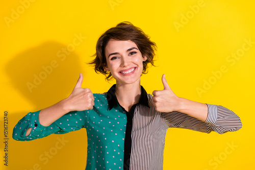 Photo of cheerful glad lovely girl wear stylish striped clothes thumb up sign isolated on yellow color background photo
