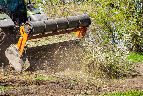 Picture of a tractor specialized in forest clearing that is in the process of destroying all the trees and bushes. Stop deforestation. Picture of a large tractor that destroys nature.